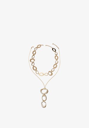 Ogrlica z zlatim tonom z ovalnimi povezavami in tremi večjimi ovalnimi obeski, ki visijo z bež vrvice.