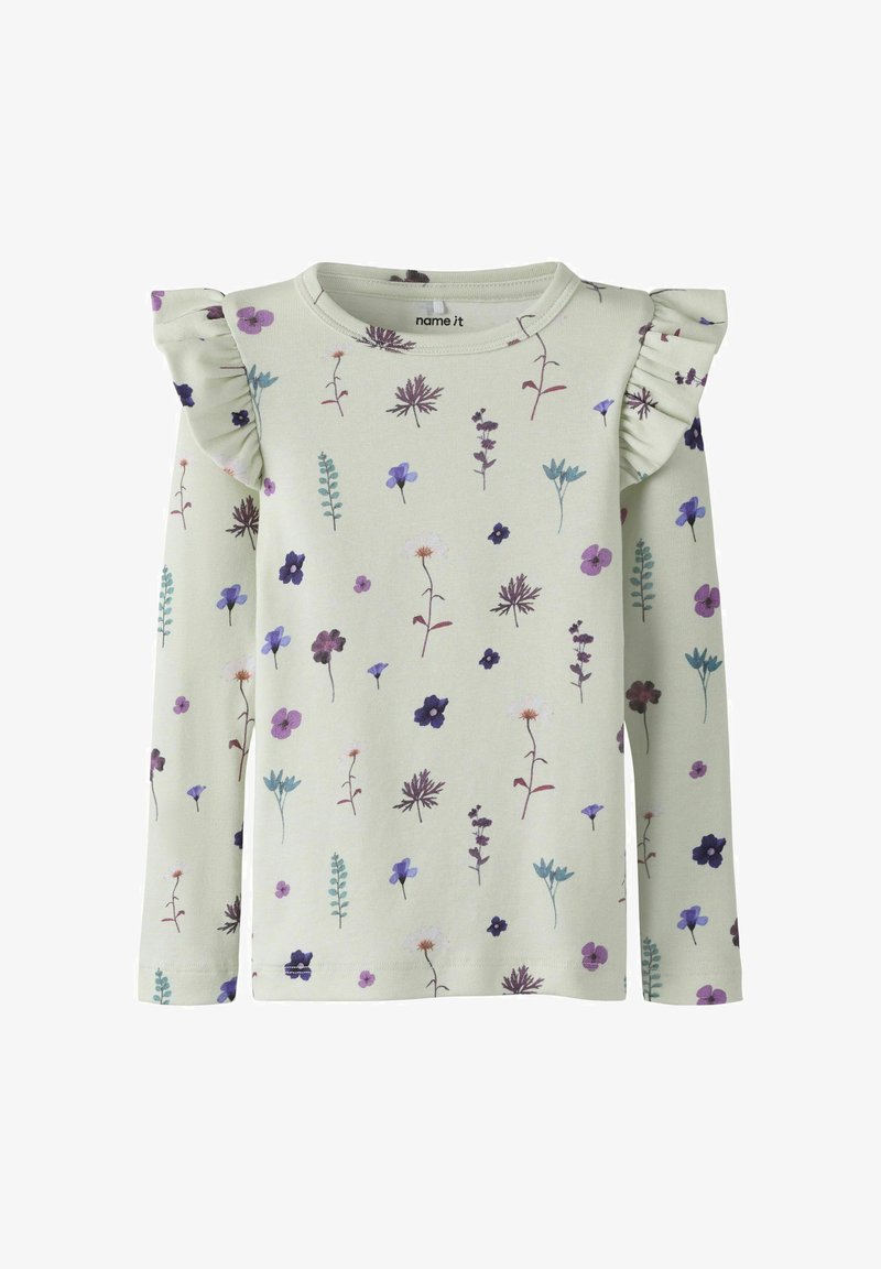 Krémová blúzka s dlhým rukávom s fialovým a modrým kvetinovým vzorom, s volánikovými detailmi na ramenách.