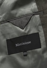 Szürke szövetbelső fekete "Matinique" feliratú címkével. Tartalmaz egy kis szürke zsebet és fekete szövetből készült méretjelzéseket.