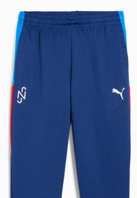 Marineblaue Jogginghosen mit elastischem Bund, ausgestattet mit blauen und roten Seitenpaneelen. Angezeigte Logos: weißes Puma-Symbol und ein stilisiertes "N2".