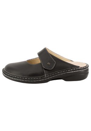 Sabots noirs à enfiler avec sangle ajustable, bout arrondi, coutures blanches visibles, intérieur beige rembourré et semelle légèrement surélevée.