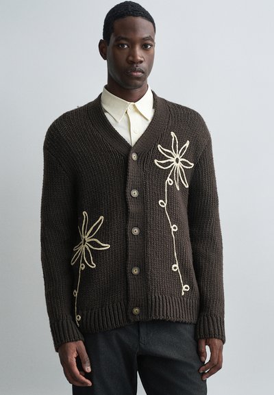 Cardigan en tricot marron avec un col en V, orné de broderies florales ivoire et d'une fermeture à boutons, à manches longues, avec des poignets et un ourlet côtelés.