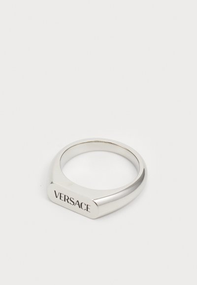 Hopea rengas, jossa on geometrinen muoto, litteä yläosa johon on kaiverrettu "VERSACE". Suorastaan sileä pinta ja kiillotus.