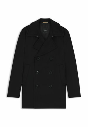Manteau noir croisé avec un col en pointe, des poches latérales et des fermetures à boutons, fabriqué dans un tissu lisse et texturé. Logo de la marque visible à l'intérieur.