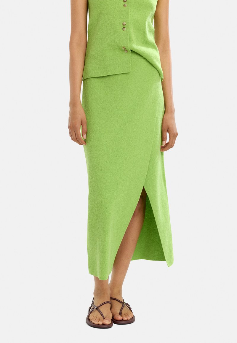 Zielony dzianinowy zestaw składający się z bezrękawowej bluzki z guzikami i spódnicy z wysokim rozporkiem. Gładka tekstura, dopasowany krój i casualowy styl.