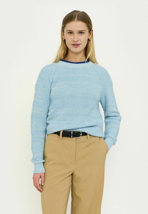 Light blue knitted sweater with ribbed texture and crew neckline, paired with beige trousers and a black belt.