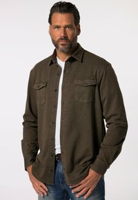 Donkergroene overhemd met knopen, gemaakt van textuurstof, met twee borstzakken en een klassieke kraag. Draag het over een wit t-shirt.
