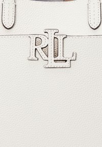 Valkoinen nahkalaukku, jossa on kohokuvioitu "RL"-logo. Pintamateriaali on teksturoitu ja siinä on näkyvät saumat sekä hihnadetails.