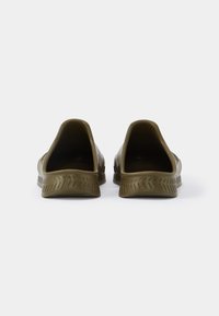 Sapatos verdes de borracha slip-on com uma abertura ampla, sola texturizada e um acabamento suave. Apresentam um design minimalista e forma arredondada.