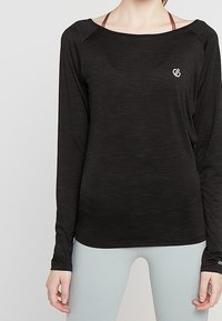 Haut de sport noir à manches longues en tissu léger, avec un col rond et une texture chinée subtile. Présente un petit logo sur la poitrine.