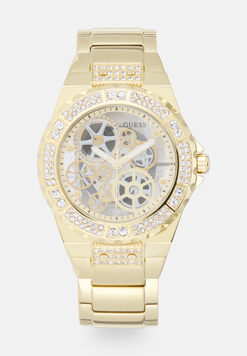 Gold-tone wristwatch with a transparent face displaying gears, surrounded by a crystal-encrusted bezel and a metallic link bracelet.