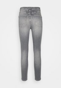 Los jeans de denim gris delgados presentan una cintura de tiro medio, un diseño de cinco bolsillos y un ligero desvanecimiento en las piernas. La tela tiene una textura suave.