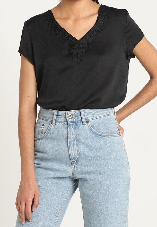 Blusa nera a maniche corte con scollatura a V, caratterizzata da dettagli in pizzo, abbinata a jeans in denim azzurro chiaro a vita alta. Tessuto morbido.