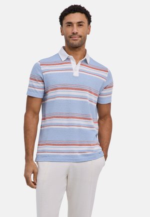 Mann trägt kurzärmeliges Poloshirt mit blauen, weißen und rostfarbenen Streifen und weißem Kragen, steht mit einer Hand in der Tasche vor weißem Hintergrund.