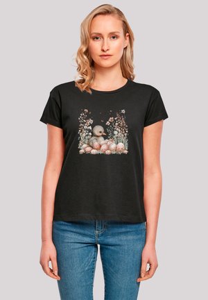 Schwarzes T-Shirt mit einem zentralen Grafikmotiv eines Entenkükens, umgeben von pinken Blumenakzenten und gesprenkelten Eiern, mit kurzen Ärmeln und einem runden Ausschnitt.