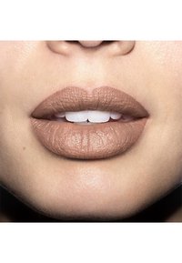 Matte nude Lippenstift auf leicht geöffneten Lippen aufgetragen, der die glatte Textur und den natürlichen Farbton zeigt, mit sichtbaren weißen Zähnen.