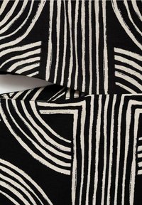 Tissu présentant des motifs géométriques audacieux en noir et crème avec des épaisseurs de ligne variées, créant un contraste visuel texturé.
