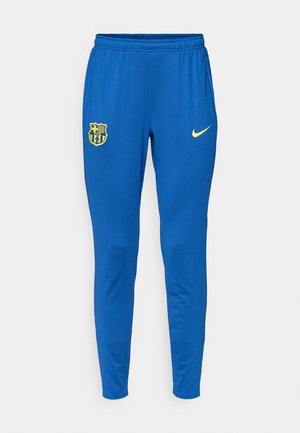 Modre atletske hlače iz gladkega blaga, z rumenim logotipom Nike in logotipom nogometnega kluba na levi stegn. Ožji kroj.