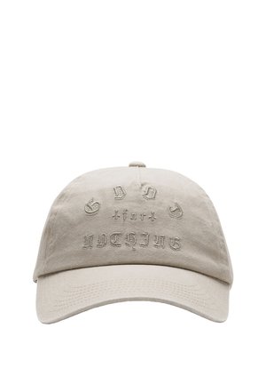 Beige katoenen baseballpet met geborduurde tekst "GOOD for NOTHING." Gebogen klep, verstelbare band aan de achterkant, zachte textuur.