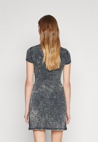 Grå randig klänning med kortärmar, figurnära design och sliten textur. Bakifrån syns en subtil midjesöm och rundad halsringning.