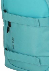 Zaino turchese in tessuto nylon testurizzato, con tasca frontale con zip, spallacci regolabili e logo stampato su un lato.