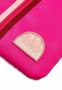 Borsa imbottita rosa con un logo ricamato beige raffigurante un motivo di sole. Il design include dettagli rosa e bordeaux lungo la cerniera.
