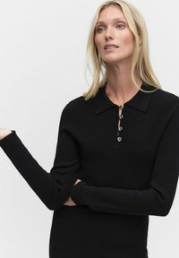 Musta pitkähihainen paita, jossa on ribbikudos, kauluspääntie ja neljä nappisuljenta etupuolella. Tiukka muotoilu, jossa on sileä pinta.