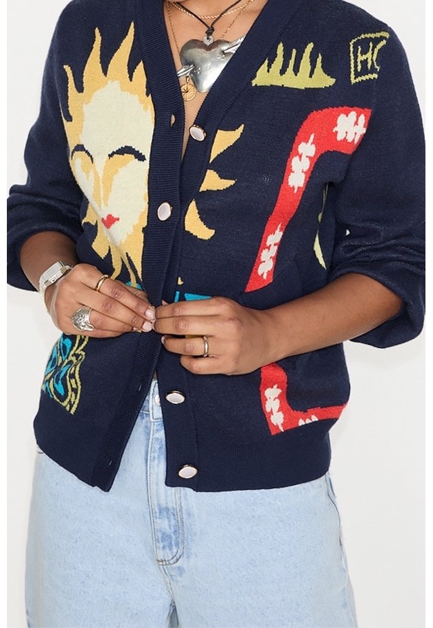 Mörkblå cardigan med färgglada sol- och grafiska mönster; knappar framtill; stickad textur; matchad med ljusblå denim.