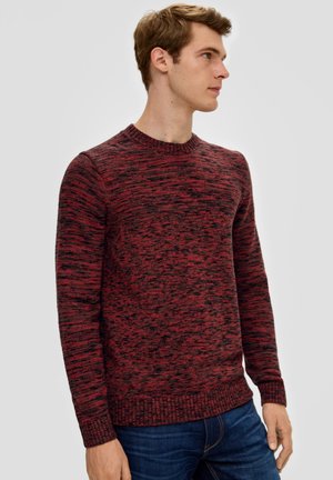 Rood en zwart gemarmerd gebreid sweater met een ronde hals, geribde mouwen en onderzoom, gecombineerd met blauwe jeans.