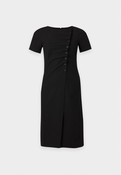 Robe noire longueur genou avec manches courtes, col rond et détail asymétrique de boutons devant sur un fond uni.