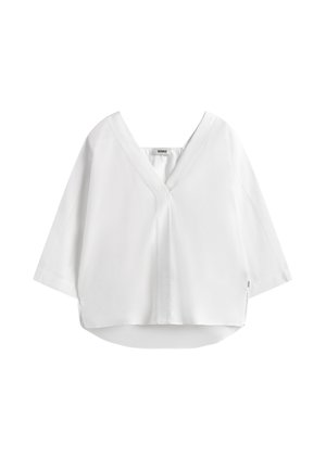 Blouse blanche ample avec col en V, manches trois-quarts et ourlet arrière légèrement plus long.