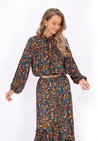 Set composto da un top corto multicolore e una gonna lunga, caratterizzato da vivaci motivi astratti arancioni, blu e verdi, maniche arricciate e vestibilità rilassata.
