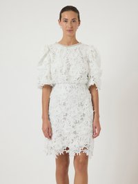 Λευκό δαντελένιο φόρεμα με λουλουδάτο σχέδιο, με φουσκωτά κοντά μανίκια και εφαρμοστή μέση. Η κόψη είναι περίτεχνα σχεδιασμένη με καμπυλωτές άκρες.