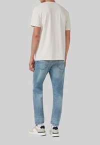 Witte katoenen t-shirt, lichtblauwe denim jeans, witte sneakers met zwarte en groene accenten. Eenvoudig ontwerp, regular fit, casual stijl.