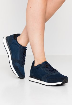 Navy blue athletic shoes with mesh and suede materials, black accents, flat white midsole, and textured rubber sole. Laced design.