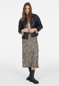 Black leather cropped jacket with a soft beige collar, paired with a leopard-print silky midi skirt and black chunky-sole ankle boots.