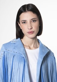 Giacca in suede azzurro chiaro con dettagli in frange e borchie argentate sulle spalle. Presenta un colletto a revers e un design minimalista.