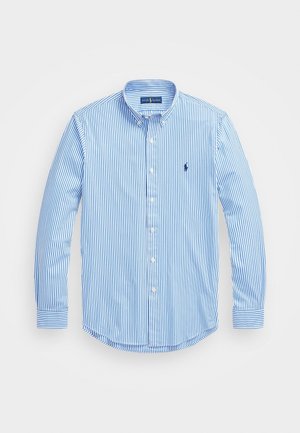 Chemise à manches longues rayée verticalement bleu et blanc, avec col boutonné et petit logo brodé sur la poitrine.