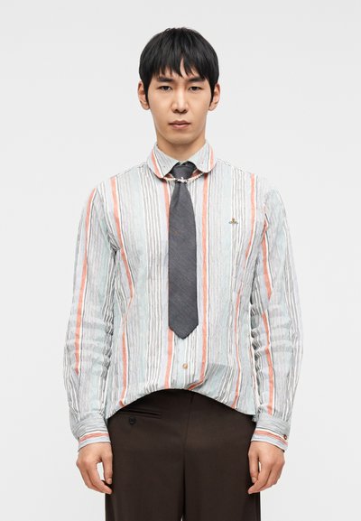 Ριγέ πουκάμισο σε ανοιχτό μπλε, λευκό και κοραλί με υφή υφάσματος. Διαθέτει γιακά με κουμπιά και γκρι γραβάτα. Καφέ παντελόνι.