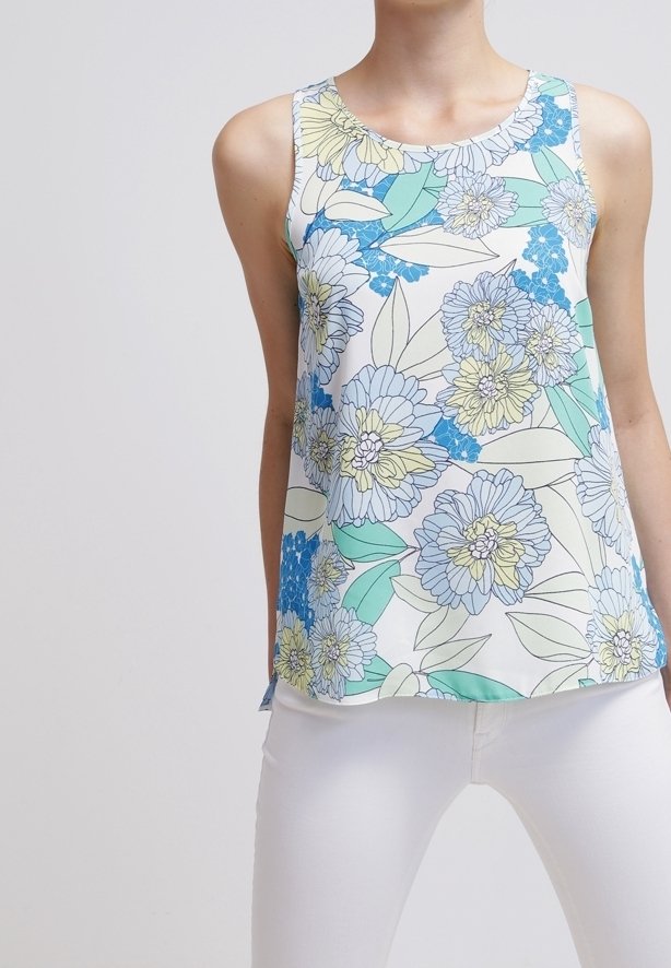 Top sin mangas con estampado floral que presenta una mezcla de flores azules, amarillas y verdes sobre un fondo blanco, hecho de tela ligera.