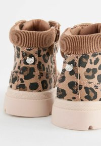 Bottes à imprimé léopard brun avec un col en velours, rehaussées d'un petit bouton en forme de chat et d'une semelle en caoutchouc rose. Design arrondi et robuste.