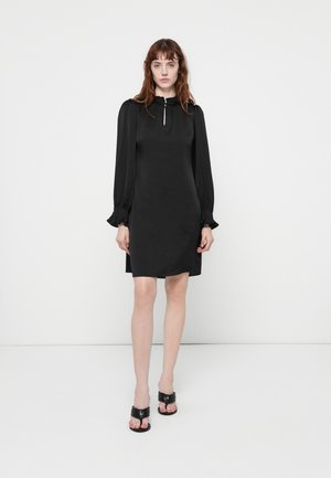 Black dress with long sleeves, high neckline, and keyhole detail. Smooth texture and fitted silhouette, ending above the knee.