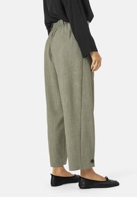 Pantaloni verde chiaro a vita alta con tessuto strutturato, design con gamba affusolata e tasche laterali, abbinati a ballerine nere.