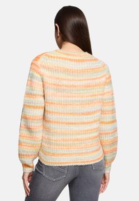 Sweter z dzianiny w wielokolorowe pasy w pastelowych odcieniach pomarańczowego, żółtego i kremowego. Posiada okrągły dekolt oraz ściągacze przy rękawach.