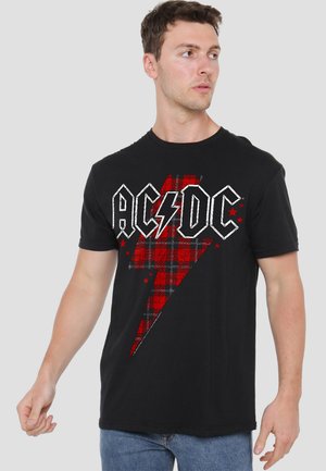 Black cotton t-shirt featuring a red plaid lightning bolt design, "AC/DC" text in white, and small red stars accenting the graphic.