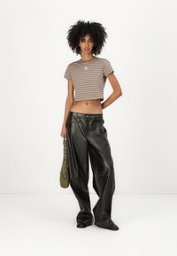 Väri ja kreemi raidallinen crop-top, yhdistettynä laajoihin mustiin nahkahousuihin. Huomionarvoisia yksityiskohtia ovat korkea vyötärö ja taskut. Vihreä laukku hihnalla.