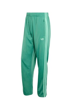 Zielone spodnie dresowe Adidas z elastycznym pasem, kieszenią na suwak po boku i trzema jasnozielonymi paskami biegnącymi wzdłuż każdej nogawki.
