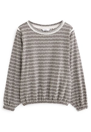 Pull blanc à manches longues avec motif triangulaire géométrique noir, poignets et ceinture froncés.