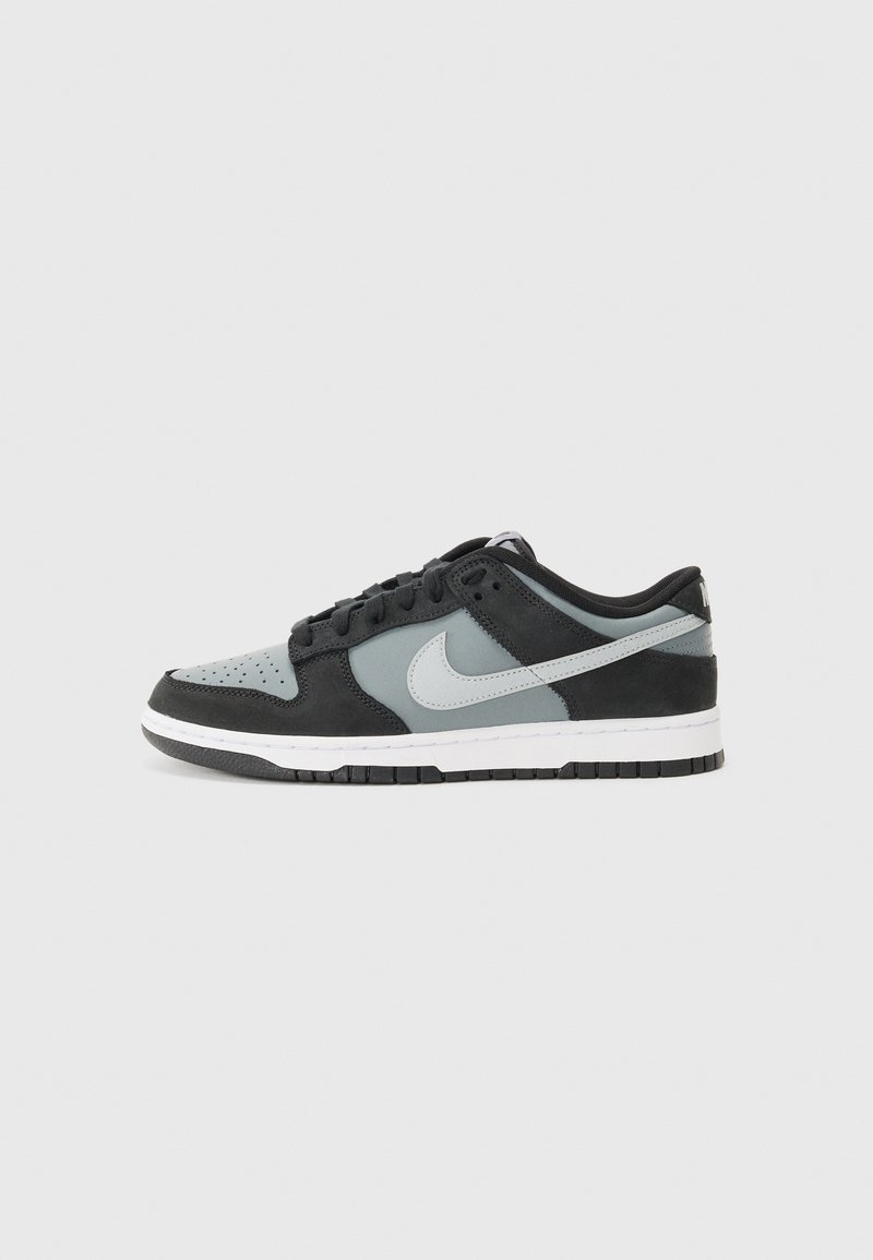 Nike sneaker, amely fekete velúrból és szürke bőrből készült. Alacsony fazonú, perforált orr résszel, fehér középtalppal és fekete gumitalppal.