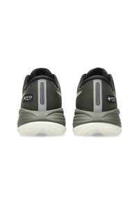 Une paire de chaussures de course Gore-Tex vert foncé vues de l'arrière, avec des rayures verticales réfléchissantes et des semelles blanches.